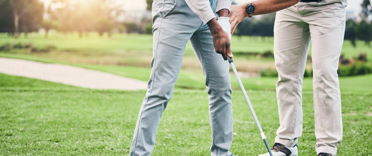 Golf coach instructing man on correct golfing posture Golf coach instructing man on correct golfing posture