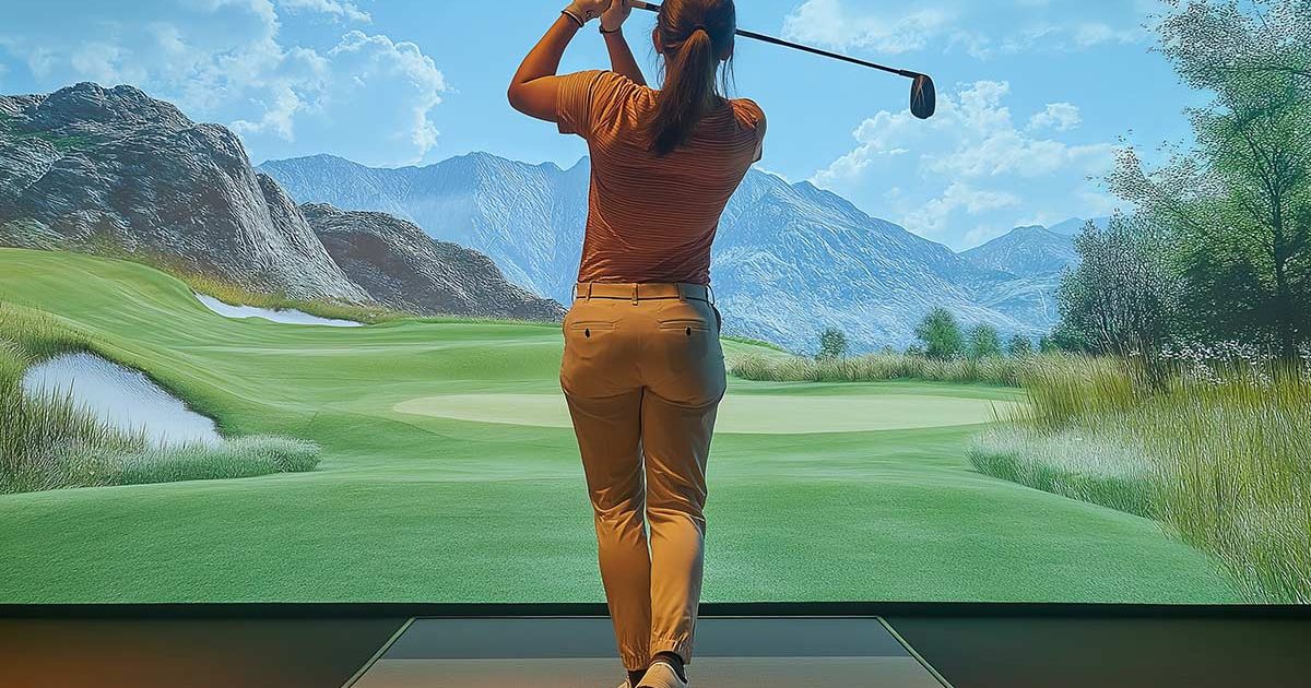 Woman in golf simulator practicing full swing Woman in golf simulator practicing full swing